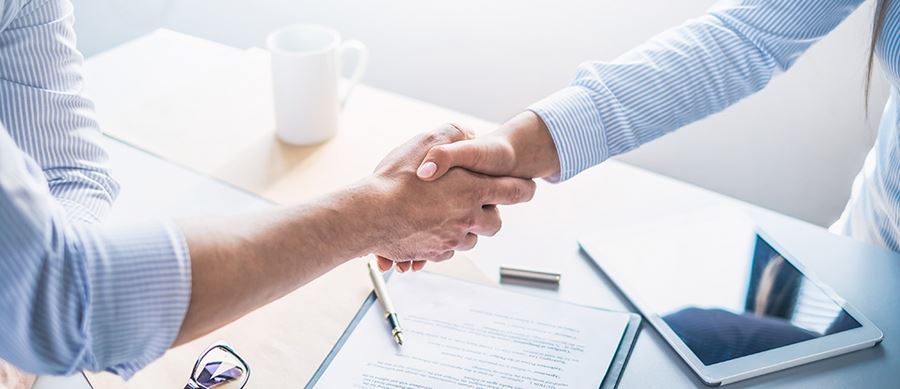 Two people shaking hands over a contract